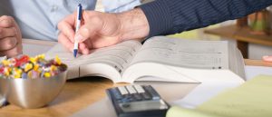 Private academic tutor explains math tutoring problem to a student. AMath tutoring book and calculator are shown.